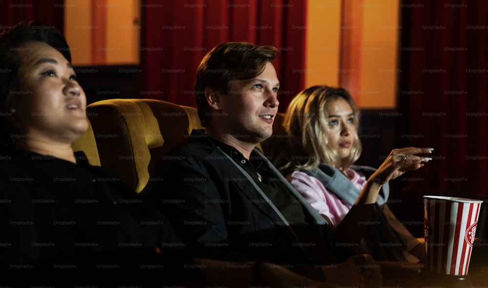 Caucasian lover and woman sitting next to them enjoying to watch movie