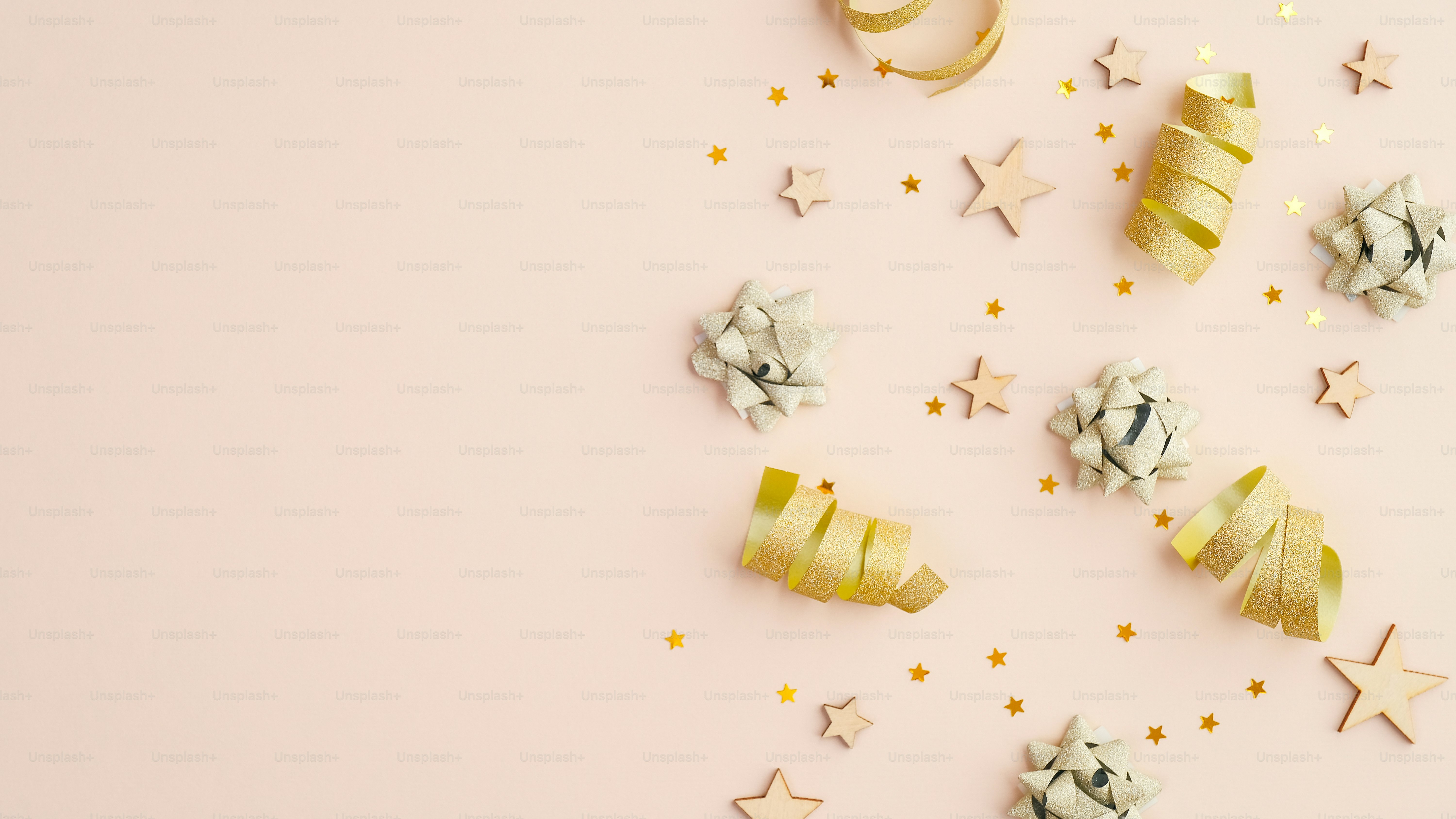 ベージュのテーブルに金色の蛇紋岩、パーティーの吹き流し、紙吹雪の星をあしらったフラットレイ構図。コピー領域付きの上面図。誕生日、クリスマスパーティー、結婚式の招待状のモックアップ。