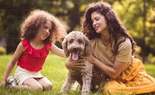 Riceve tutto il nostro amore e la nostra attenzione. Madre e figlia che giocano con il cane nel parco.