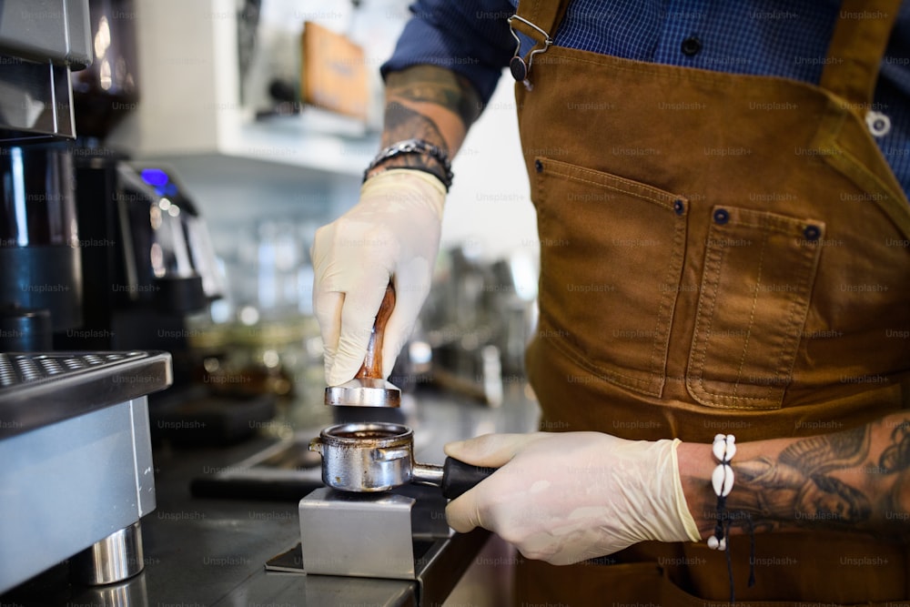 Hipster barista working with gloves, coffee shop open after lockdown quarantine.