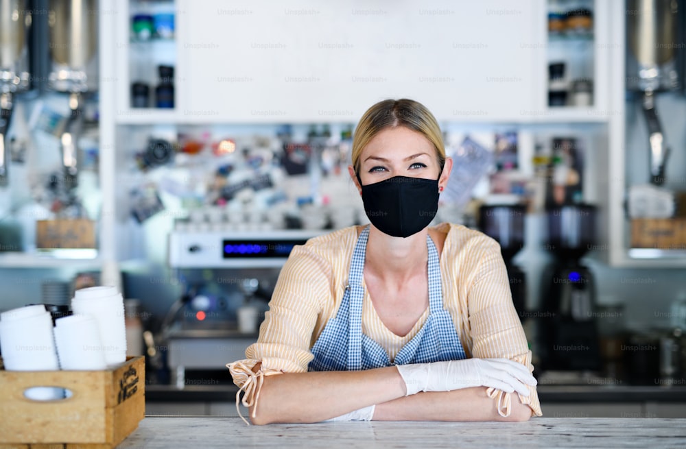 Femme propriétaire avec un masque facial dans un café, confinement, quarantaine, coronavirus, concept de retour à la normale.