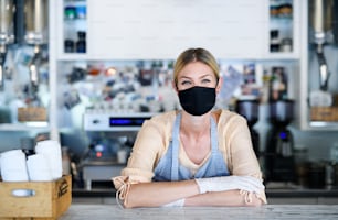 Woman owner with face mask in coffee shop, lockdown, quarantine, coronavirus, back to normal concept.