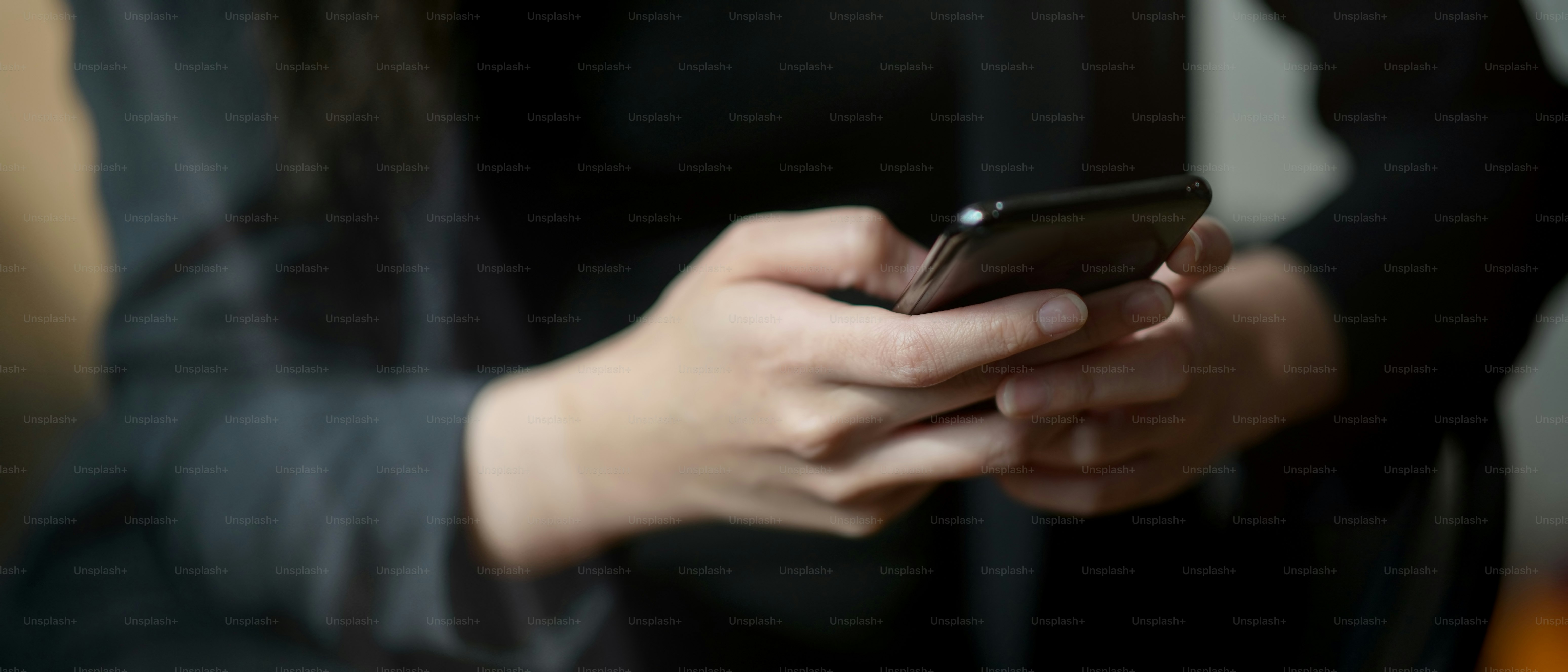 Nahaufnahme von Geschäftsleuten, die SMS auf dem Smartphone schreiben, während sie im Büroraum sitzen