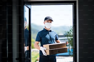Vista frontale del corriere con maschera facciale e guanti che consegna pacco, corona virus e concetto di quarantena.