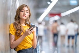 Giovane bella ragazza adolescente asiatica che usa lo smartphone nella stazione della metropolitana.