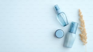 Frascos cosméticos de higiene pessoal azuis e flor seca no fundo azul. Vista superior, flat lay. Conjunto de produtos de beleza à base de água, estilo minimalista.