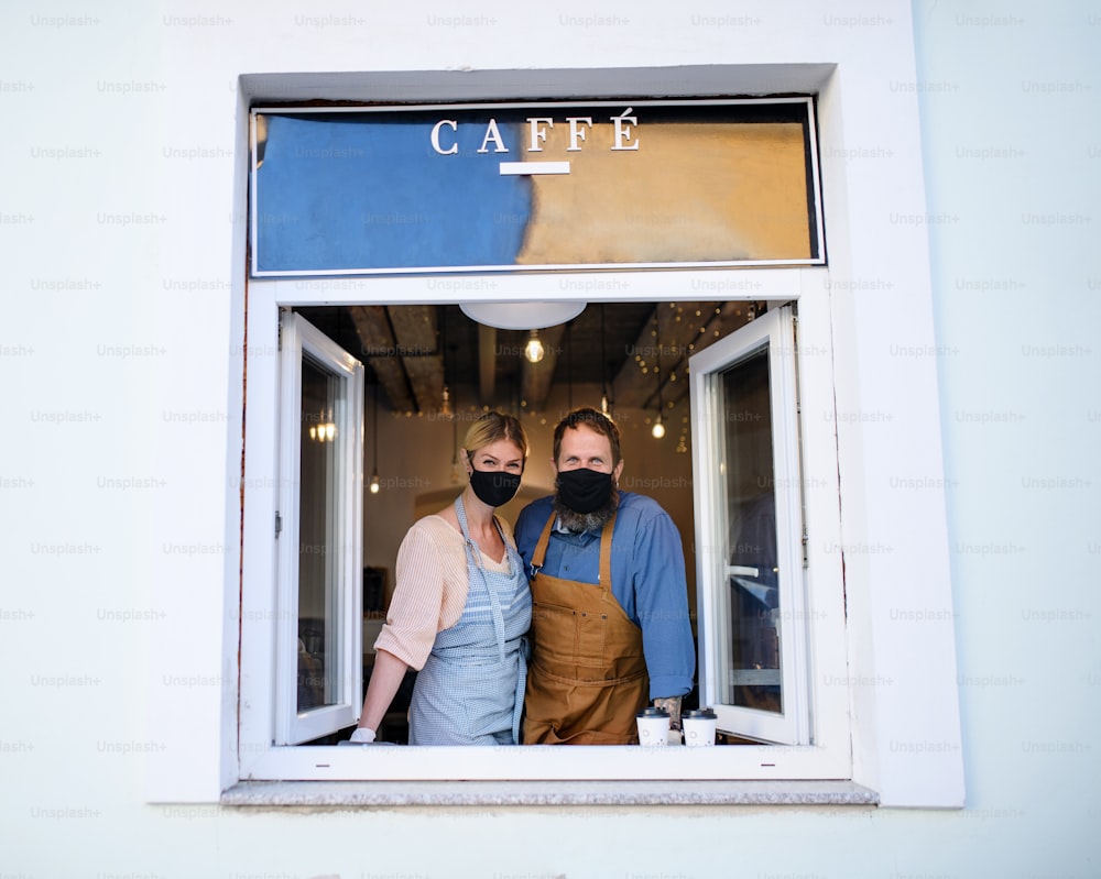 Retrato de los propietarios de una cafetería con mascarillas, encierro, cuarentena, coronavirus, vuelta a la normalidad.