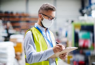 Porträt eines Technikers oder Ingenieurs mit Schutzmaske, der in einer Industriefabrik arbeitet, schreibt.