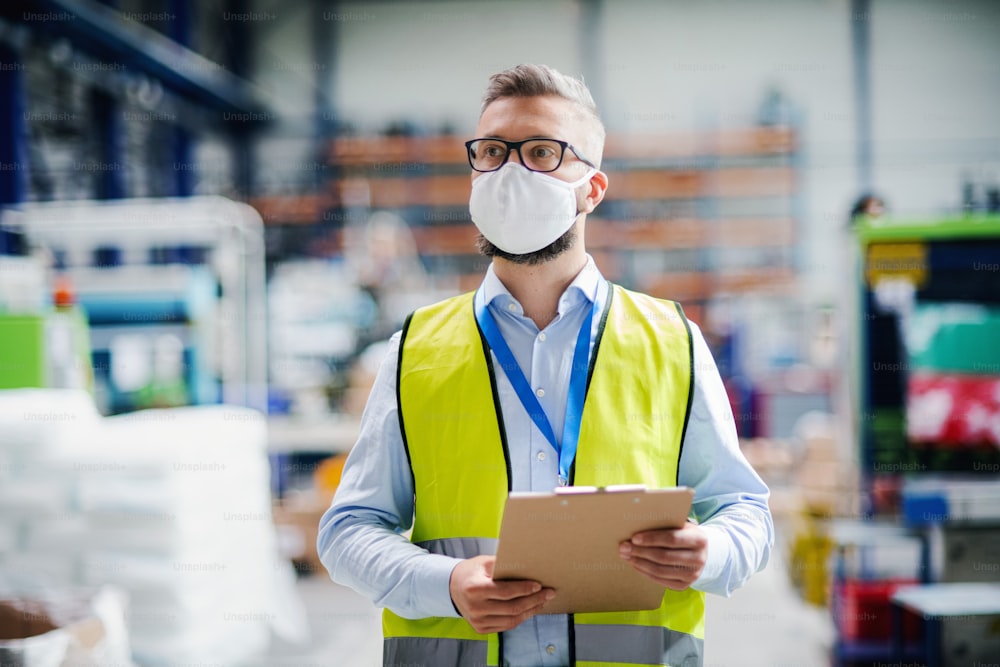 Retrato de un técnico o ingeniero con máscara protectora trabajando en una fábrica industrial, caminando.