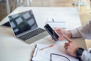 Businessman using mobile phone while working at home with a laptop computer.