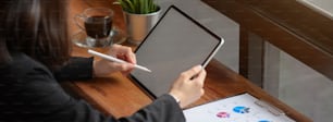 Cropped shot of businesswoman working on mock-up tablet with stylus pen and paperwork on wooden counter bar