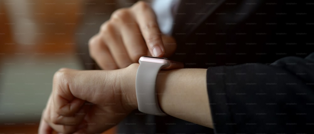 Foto cortada de uma mulher usando smartwatch para verificar mensagens enquanto está na sala do escritório