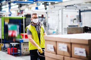 Portrait d’un ouvrier avec un masque de protection travaillant dans une usine industrielle ou un entrepôt.