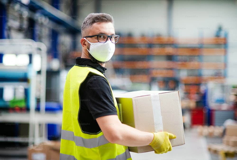 Portrait of man worker with protective mask working in industrial factory or warehouse.