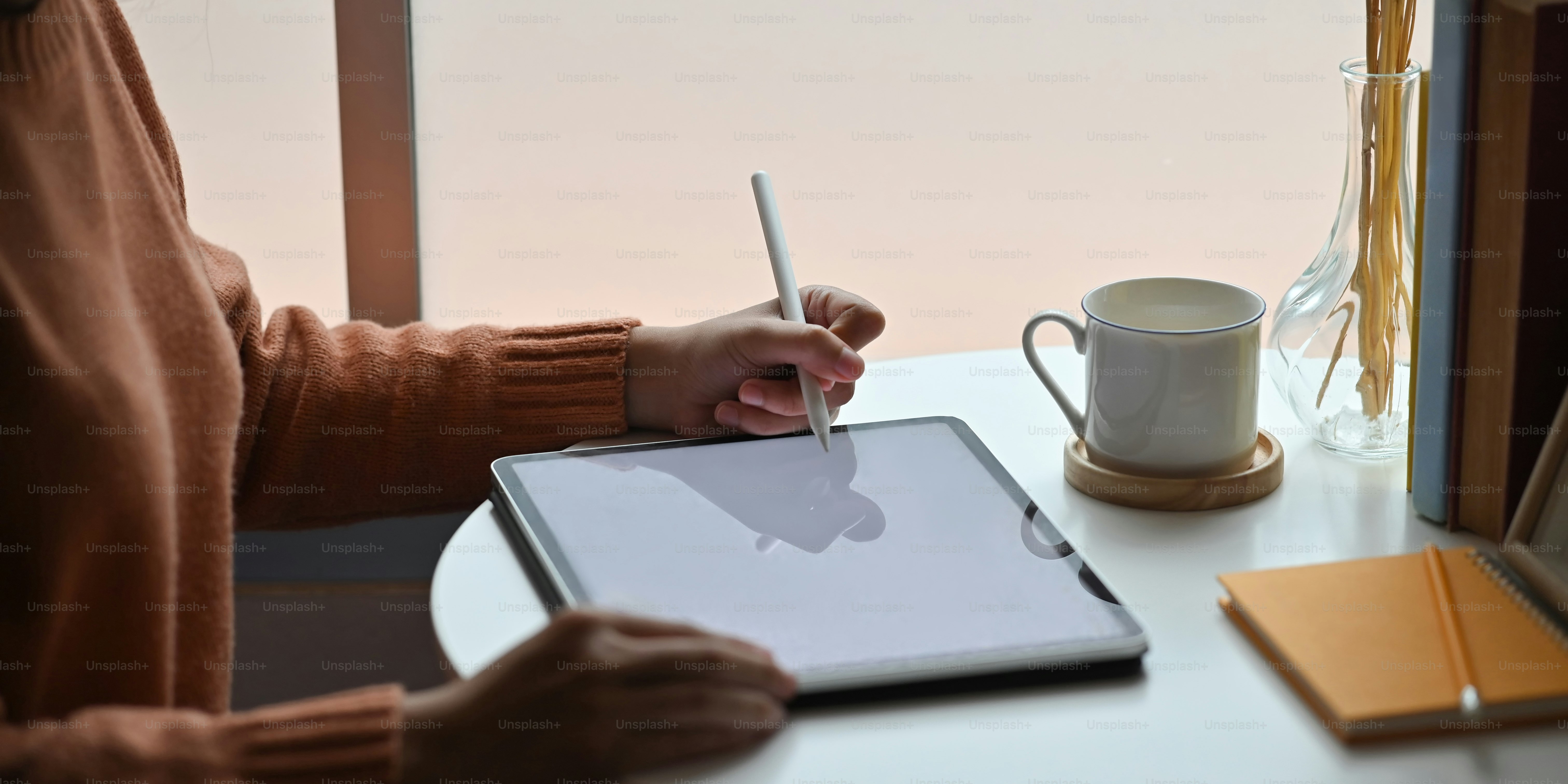 Closeup woman drawing/sketching on computer tablet by using a stylus pen while sitting at the working desk over comfortable.