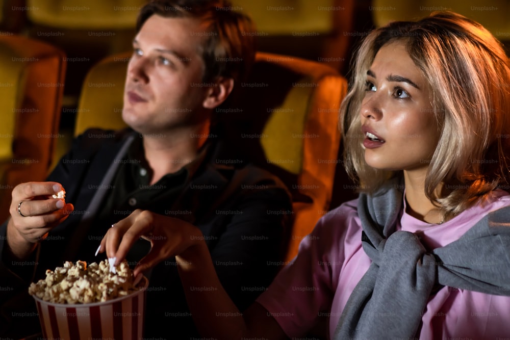 Amante caucasiano gostando de assistir filme e comendo pipoca juntos no cinema