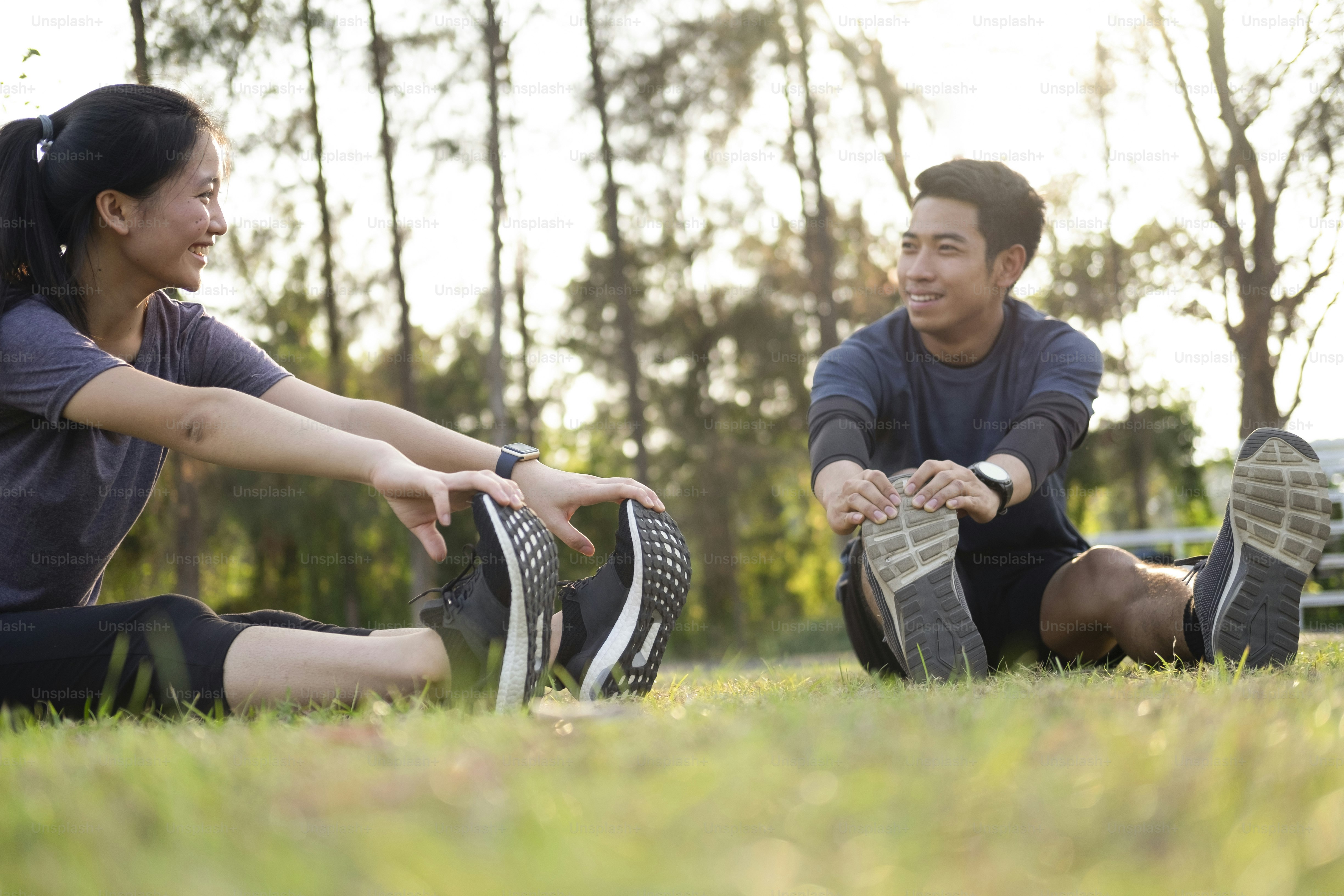 Young man and woman stretching in the park. Young couple cool down after workout exercise.