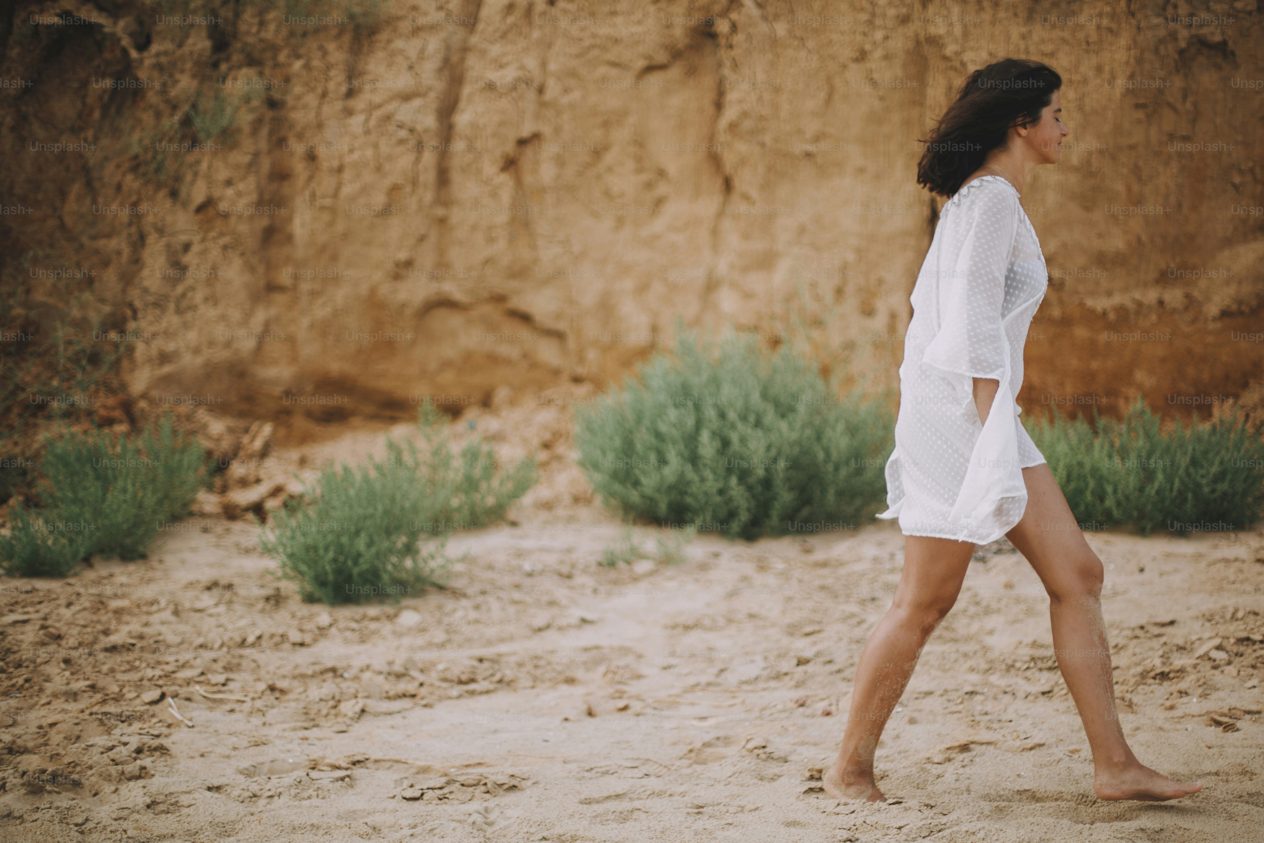 Chica boho despreocupada en vestido blanco de verano caminando por la playa. Joven feliz relajándose en la orilla del mar. Veraneo. Mindfulness y relajación. Modo de vida