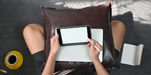 The top view image of a smart man is drawing on a white blank screen computer tablet that putting on his lap by using a stylus pen.