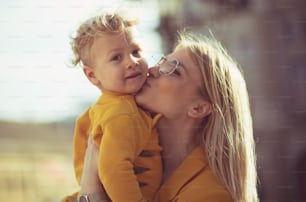 Mom is full of kisses for her child. Mother and son in the city.