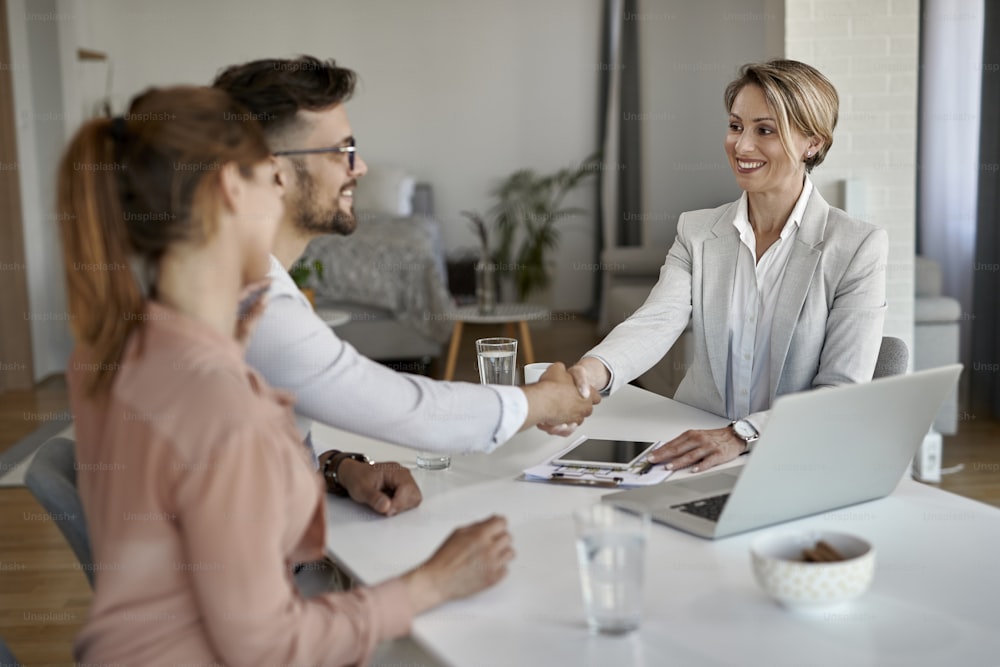 Happy real estate agent greeting a couple while having a meeting in the office.