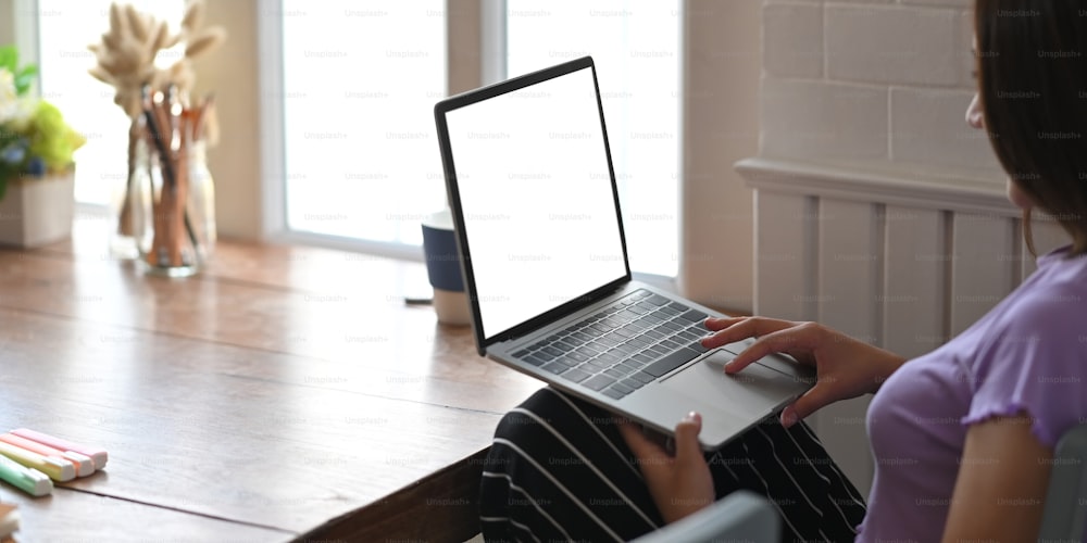 L'immagine ritagliata delle mani di una donna sta digitando su un computer portatile che mette in grembo.