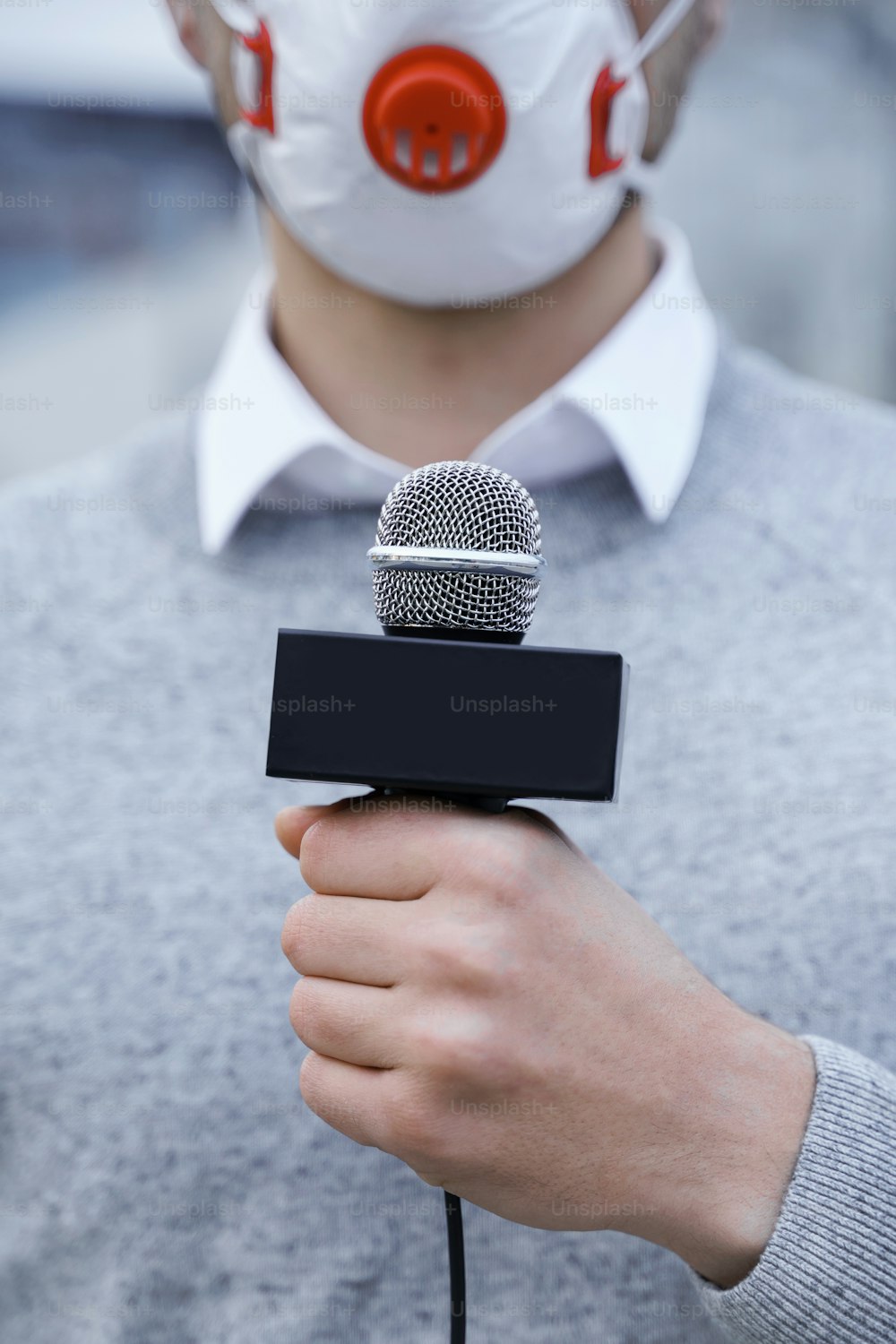 Nachrichtenreporter trägt eine Präventionsmaske und spricht während der Sendung in ein Mikrofon