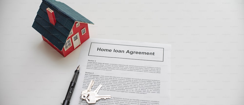 흰색 테이블에 펜, 집 모델 및 집 열쇠가 있는 주택 대출 계약의 자른 샷