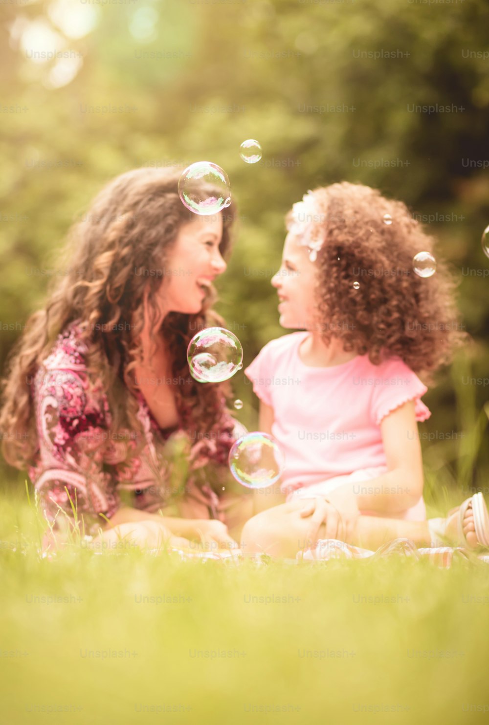 Bubbles time. Mother and daughter in nature. Focus is on bubble.