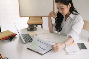 Junger asiatischer Unternehmer, der denkt und wichtige Entscheidungen am Arbeitsplatz trifft. Konzentrierte ernsthafte Büroangestellte Millennial-Frau, die Ergebnisse analysiert.