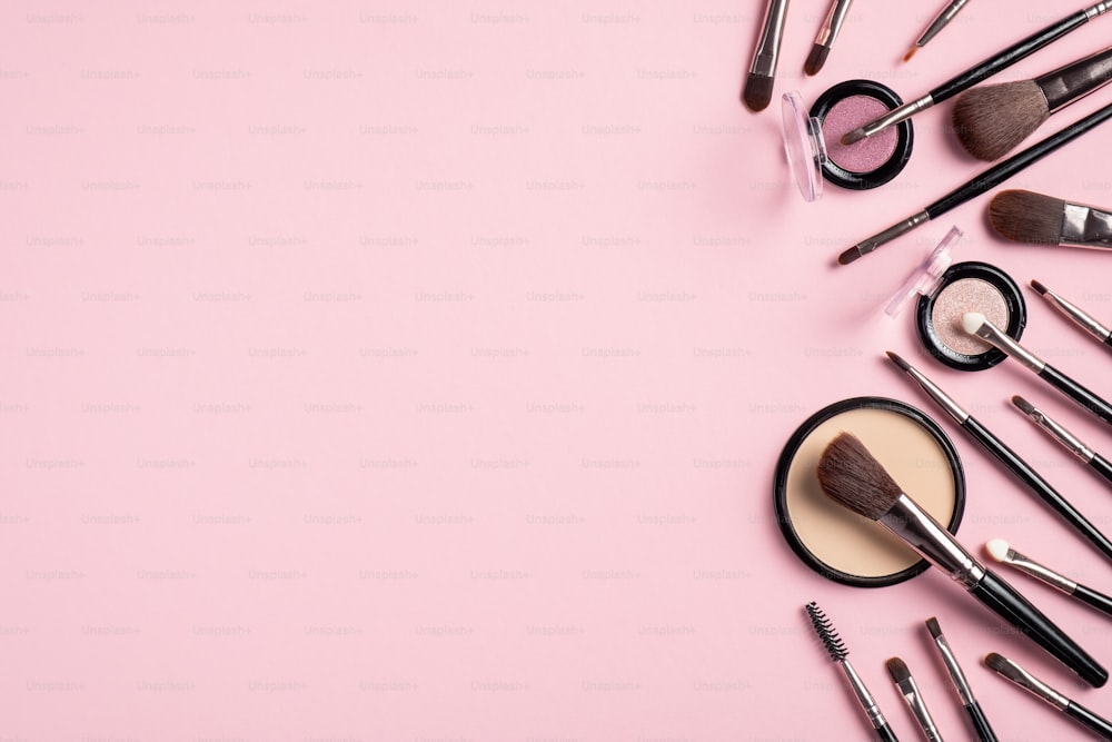 Composição flat lay com pincéis de maquiagem e cosméticos faciais isolados em fundo rosa. Vista superior com espaço de cópia. Maquete de banner de salão de beleza. Conjunto de maquiagem cosmética da moda