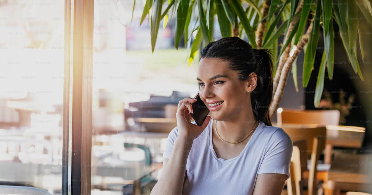 Calling Alone Young charming woman calling with cell telephone while sitting alone in ...