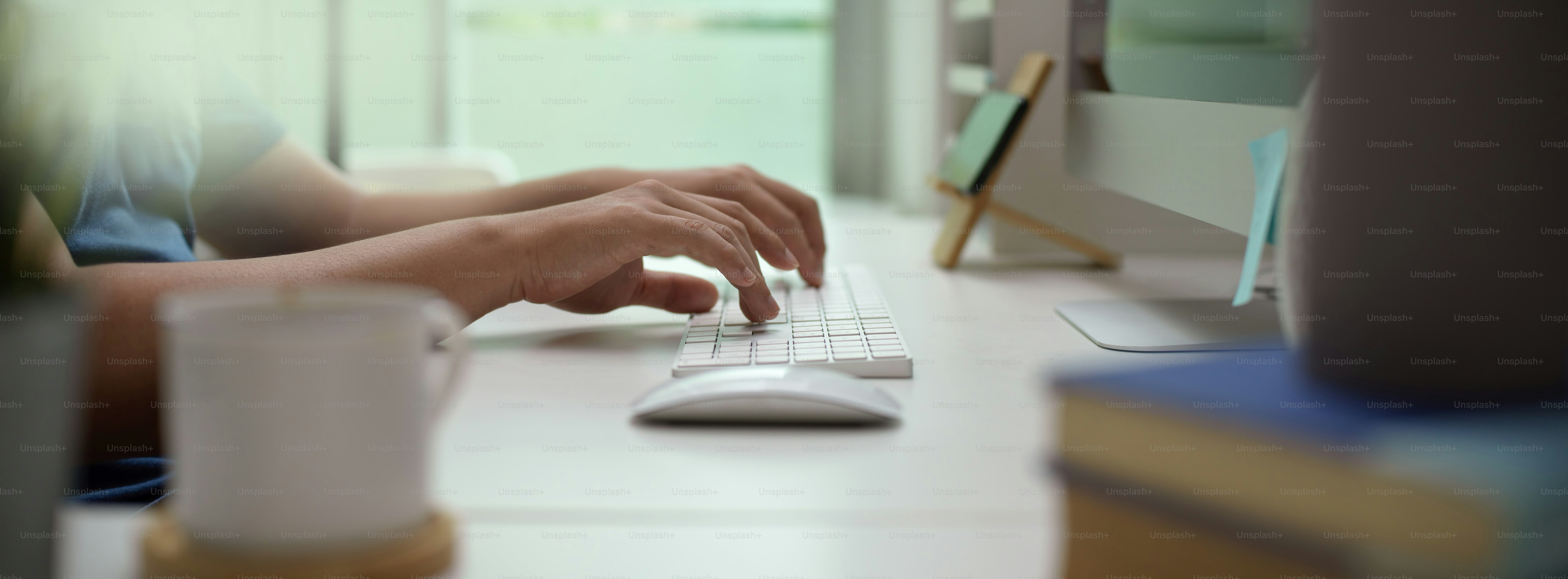 Side view of male entrepreneur typing on computer device on white office desk in modern office room