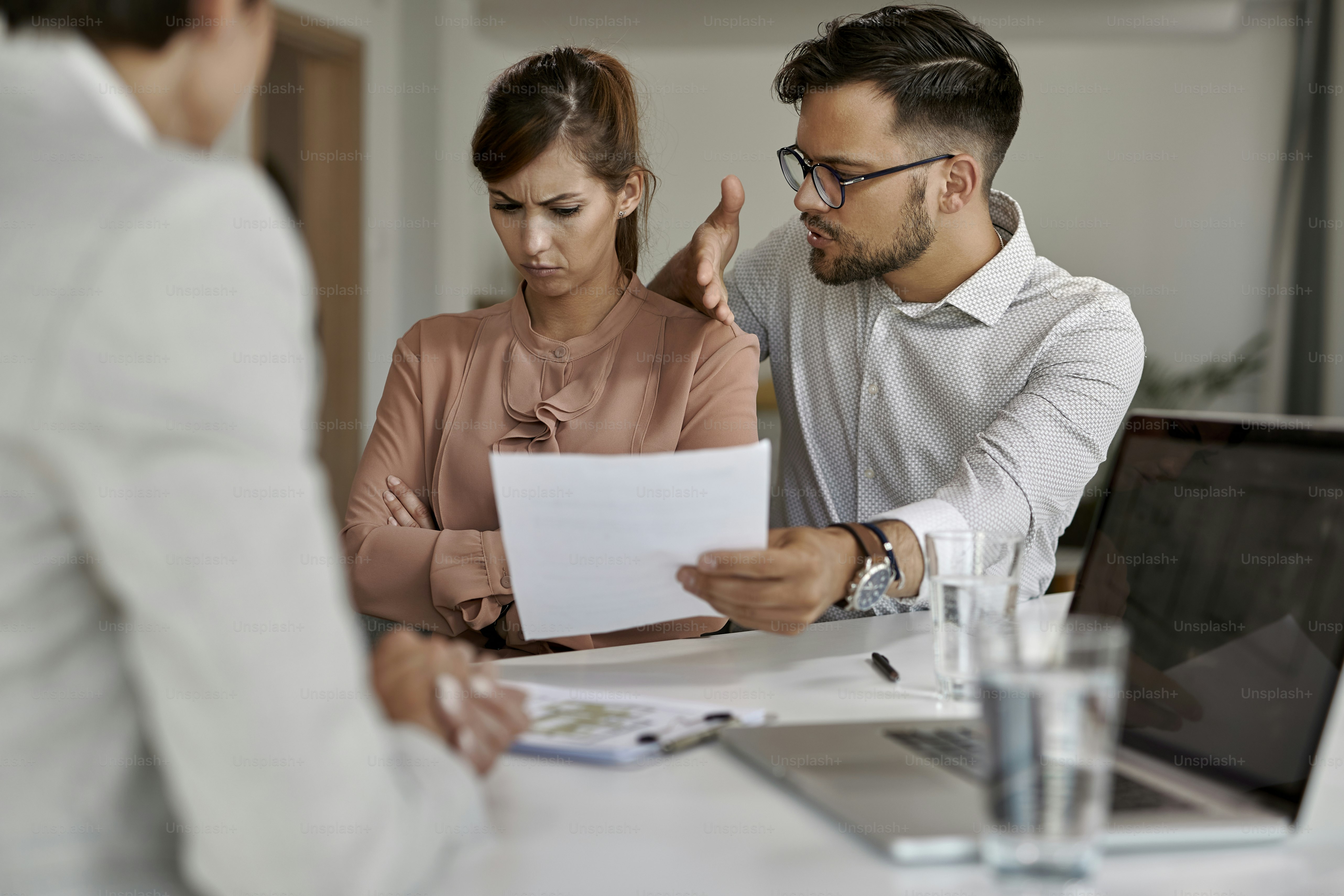 Young man trying to talk with his stubborn wife while analyzing lease agreement on a meeting with real estate agent.