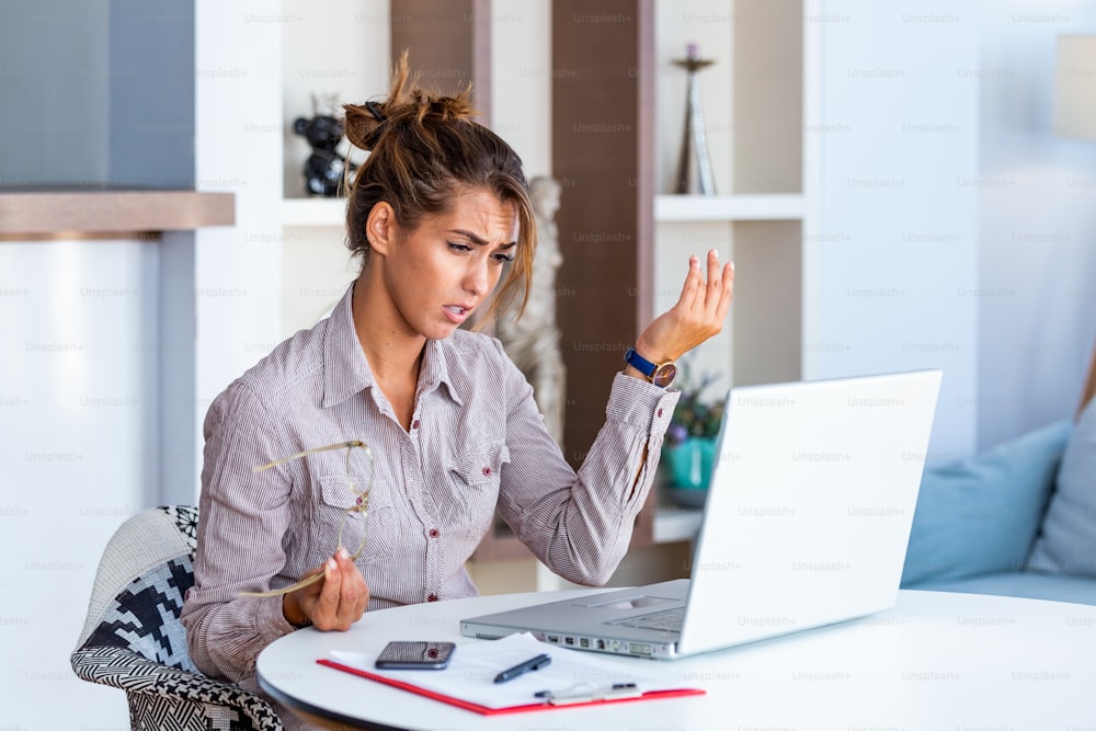 Young businesswoman misunderstanding her laptop at her desk in office. woman working with laptop at home or modern office. Serious, confused, or frustrated expression.