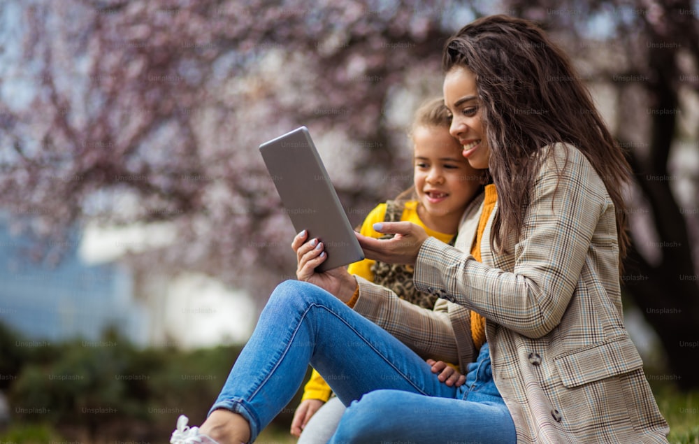 A tecnologia está lá para preencher o nosso dia às vezes. Mãe afro-americana com sua filha no parque.