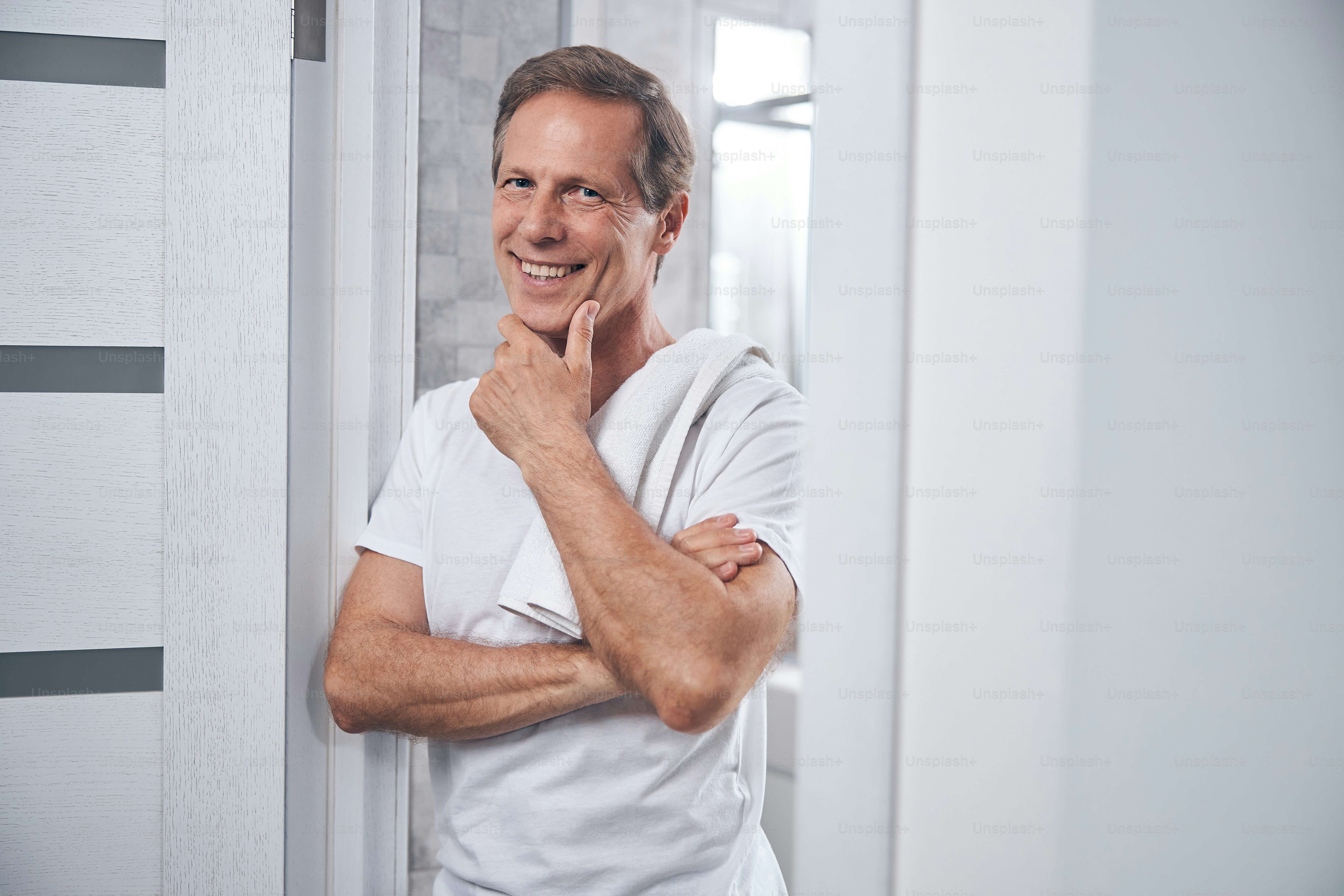 Waist-up portrait of a happy man in a t-shirt propping his chin on his ...