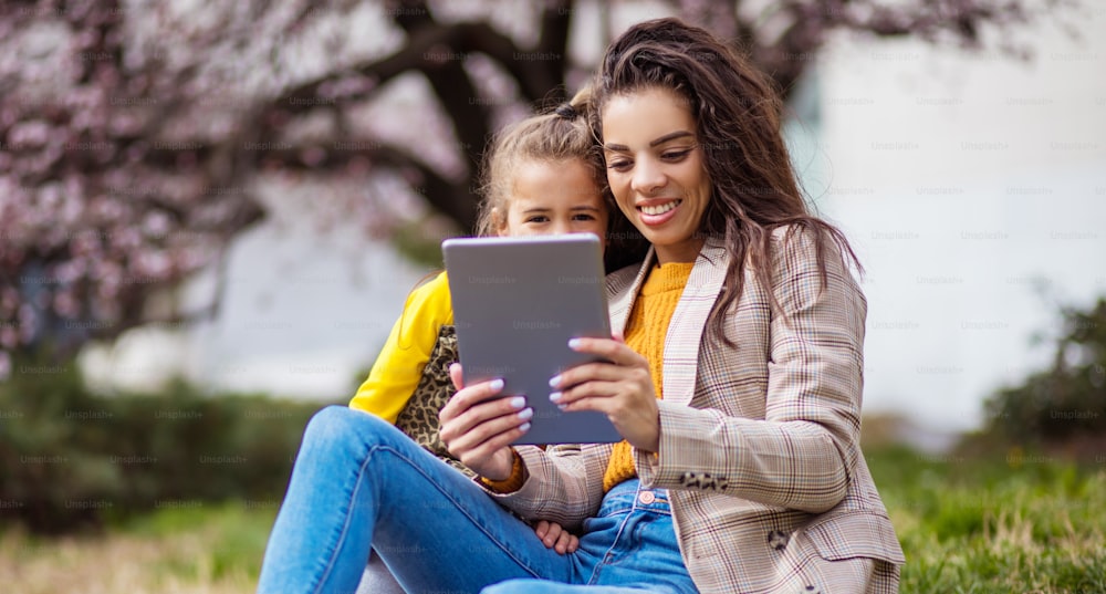 Explora la naturaleza a través de Internet. Madre e hija en el parque de la ciudad usando una tableta digital.