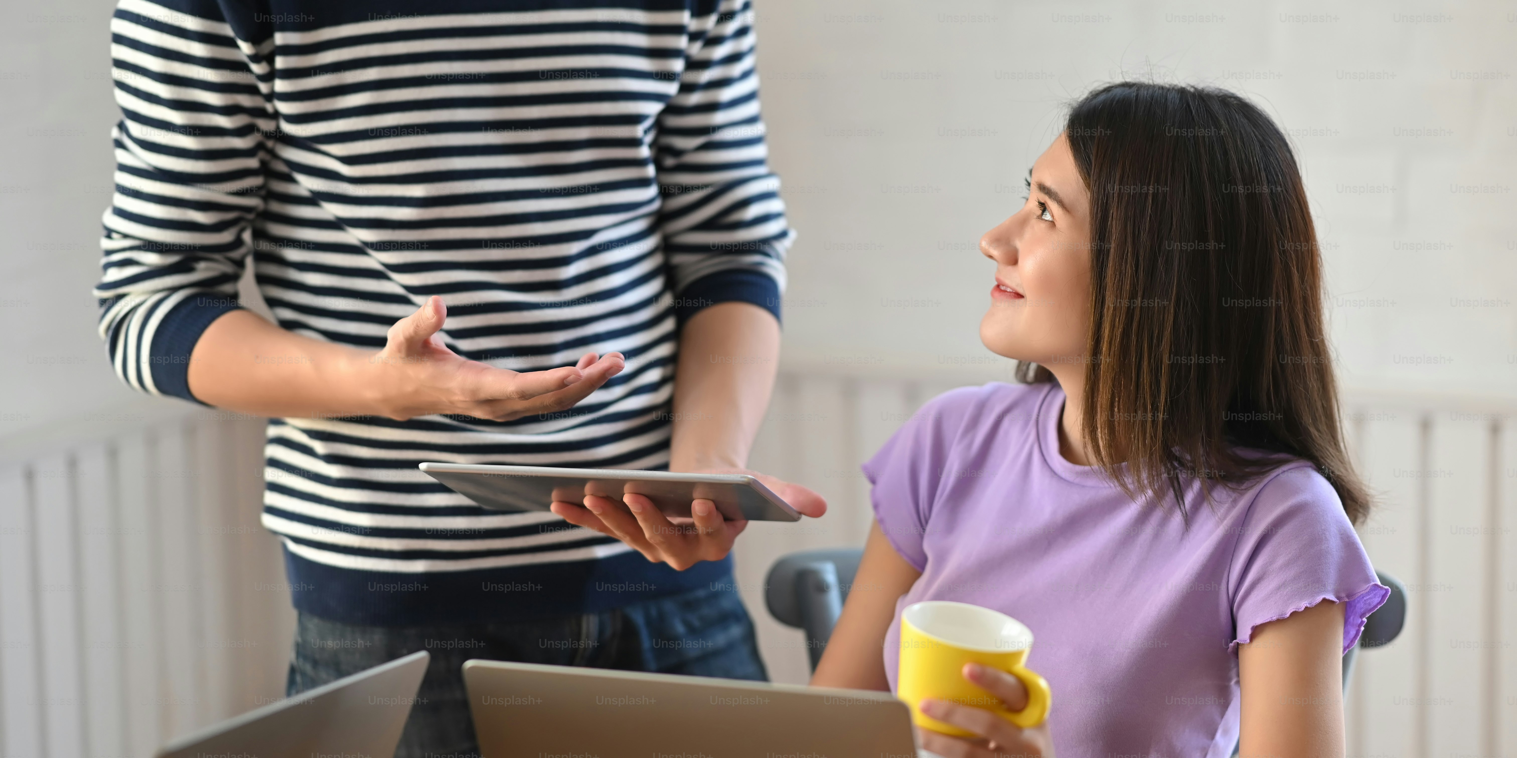 A young couple is working together with a computer laptop and tablet at the wooden working desk.
