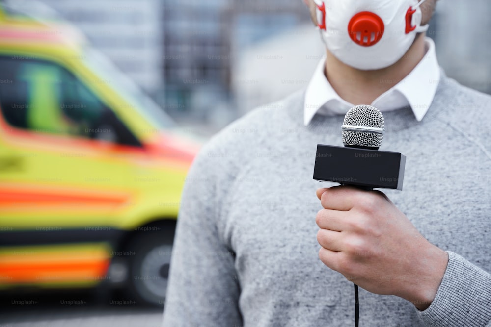 Reportero de noticias con una máscara de prevención y hablando por un micrófono durante la transmisión