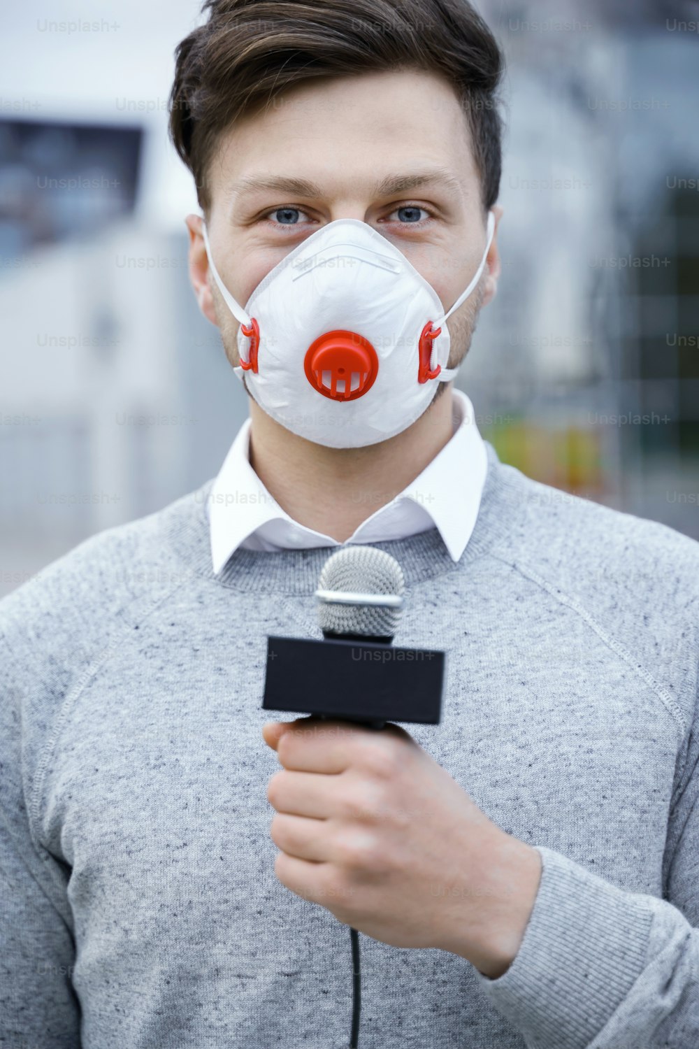 Reportero de noticias con una máscara de prevención y hablando por un micrófono durante la transmisión