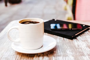 coffee cup and smart phone outdoors on a table at coffee shop or cafe with blurred background