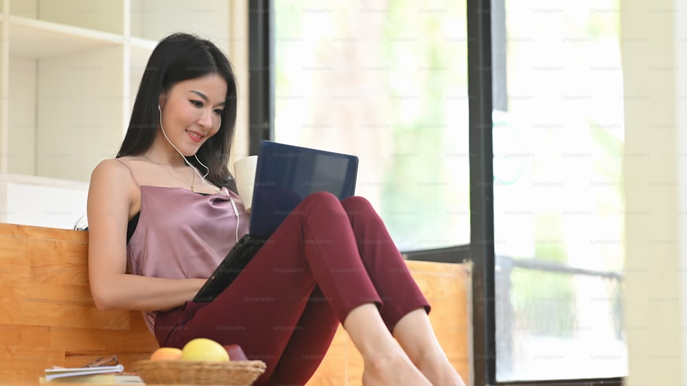 A woman is relaxing with a computer laptop while sitting on a wooden bench.