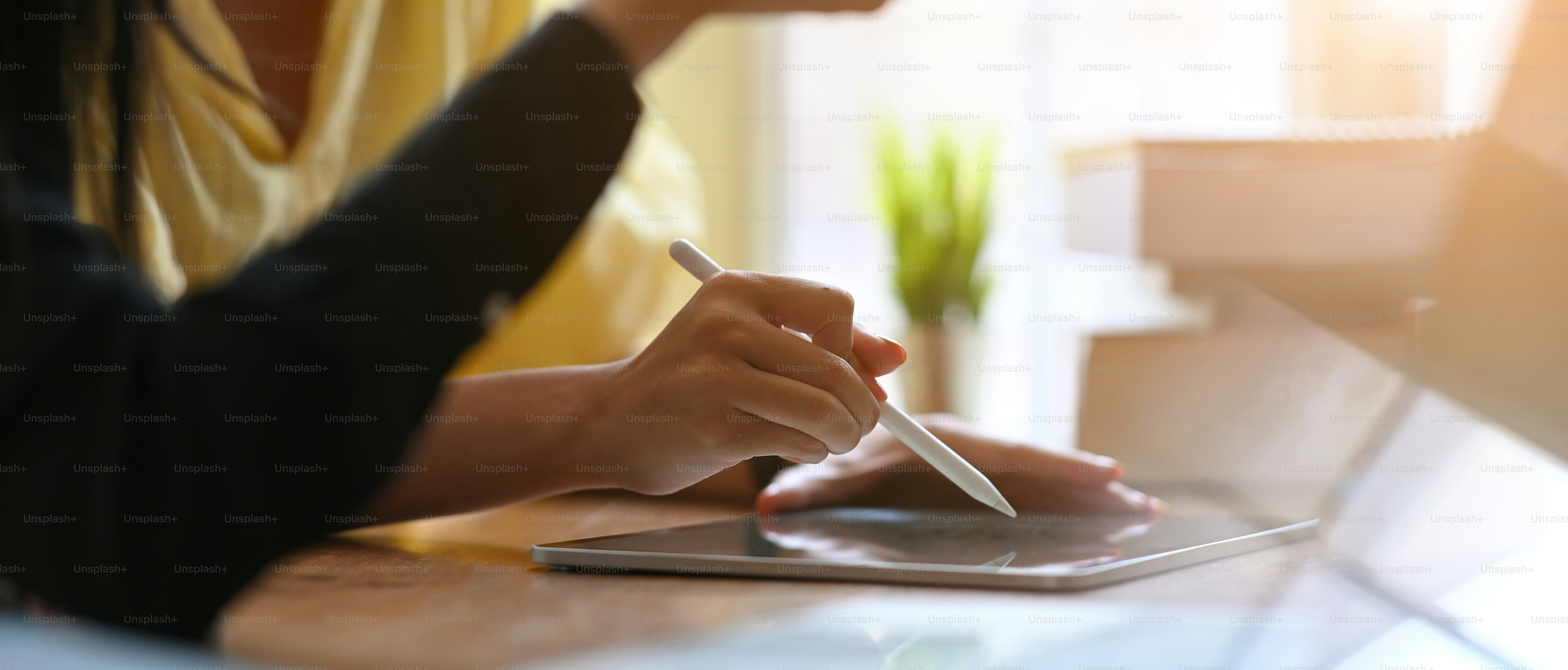 Businesswomen are working together by using a computer laptop and tablet at the wooden working desk.