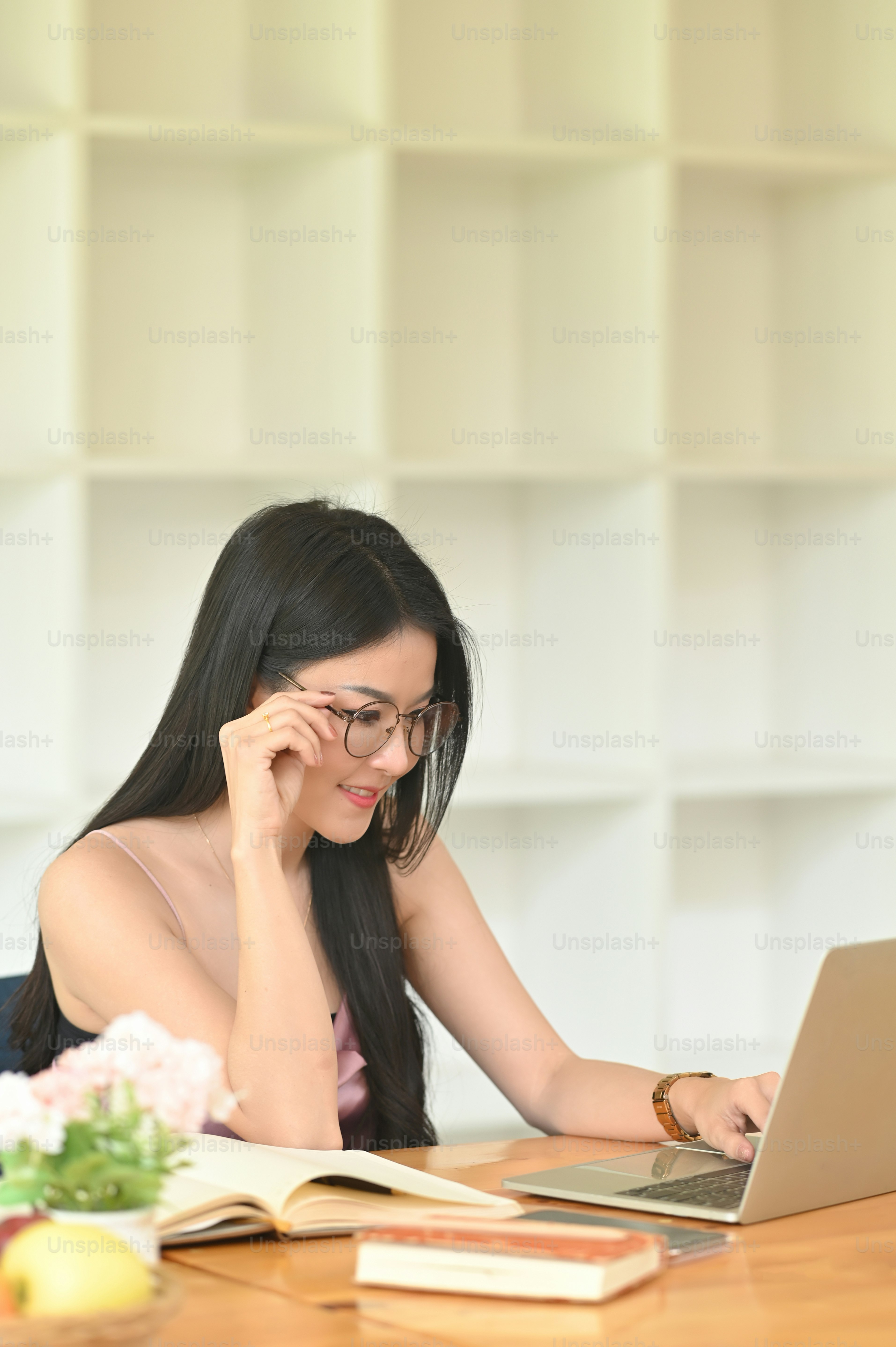 A woman with glasses is using a computer laptop while sittin