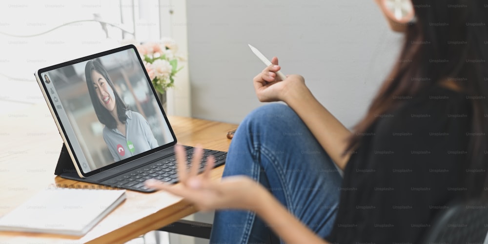 Une jeune femme fait une vidéoconférence avec des collègues sur le bureau en bois.
