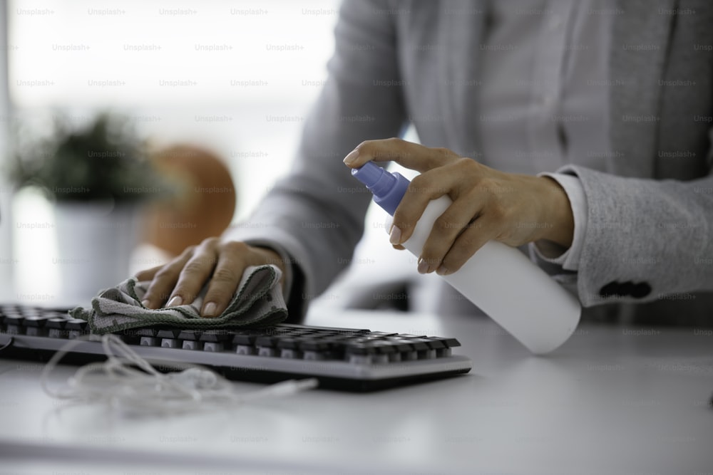 Businesswoman disinfecting her laptop keyboard in the office.