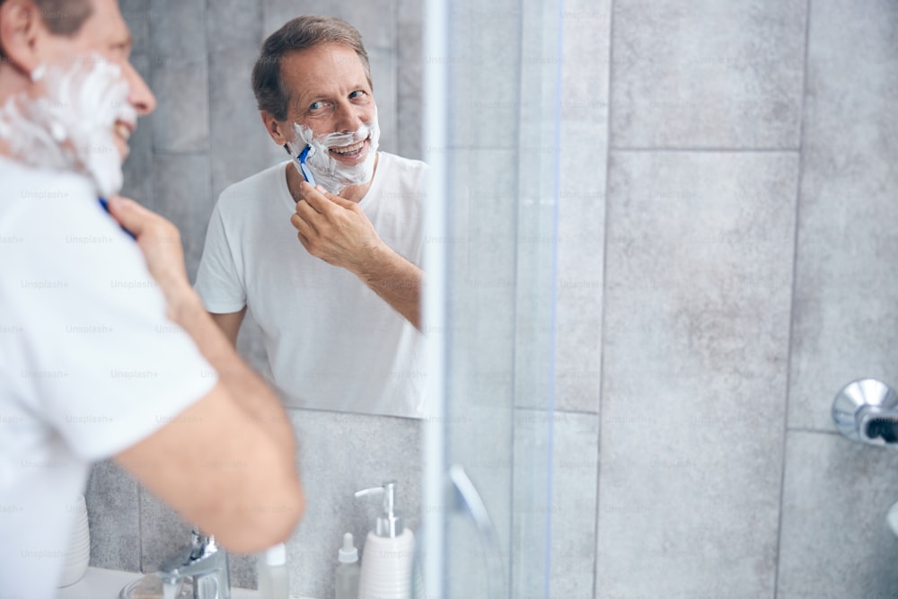 Retrato de un hombre con una navaja de afeitar en la mano mirando en el espejo
