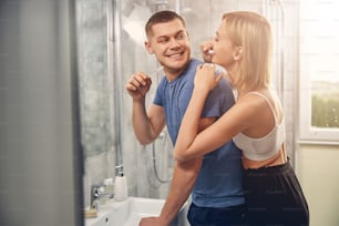 Smiling young couple caring about hygiene while standing in bathroom at home