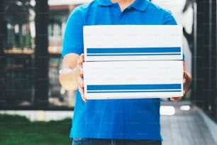 Repartidor sosteniendo cajas de cartón. Compras en línea y entrega exprés.